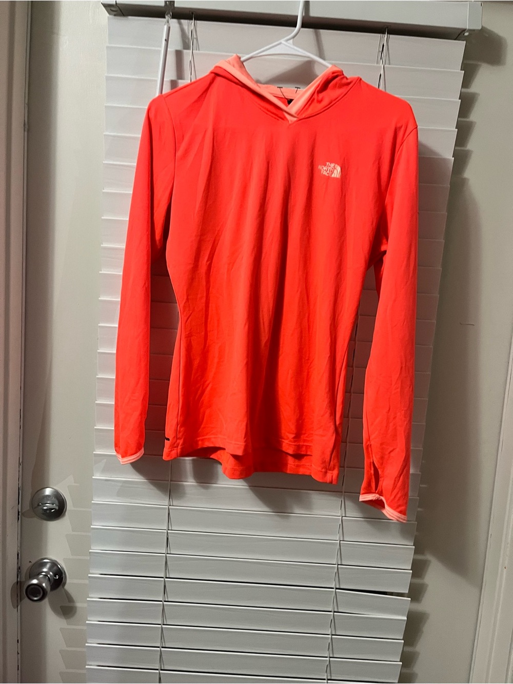 The North Face women Bright Neon Coral Hooded Sun Top. It has a small hole at
